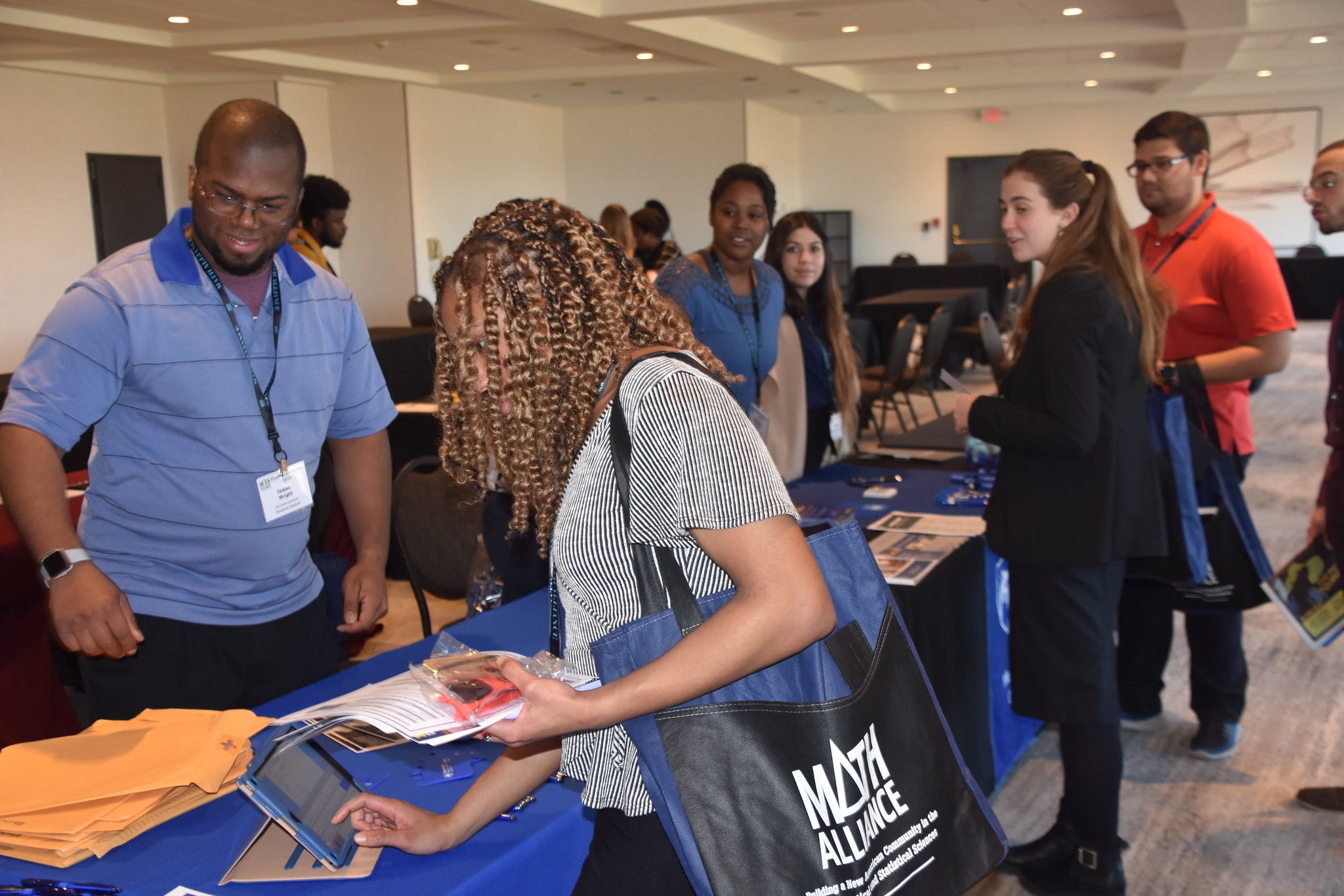 Photo of attendees picking up graduate fair materials at Field of Dreams Conference registration table